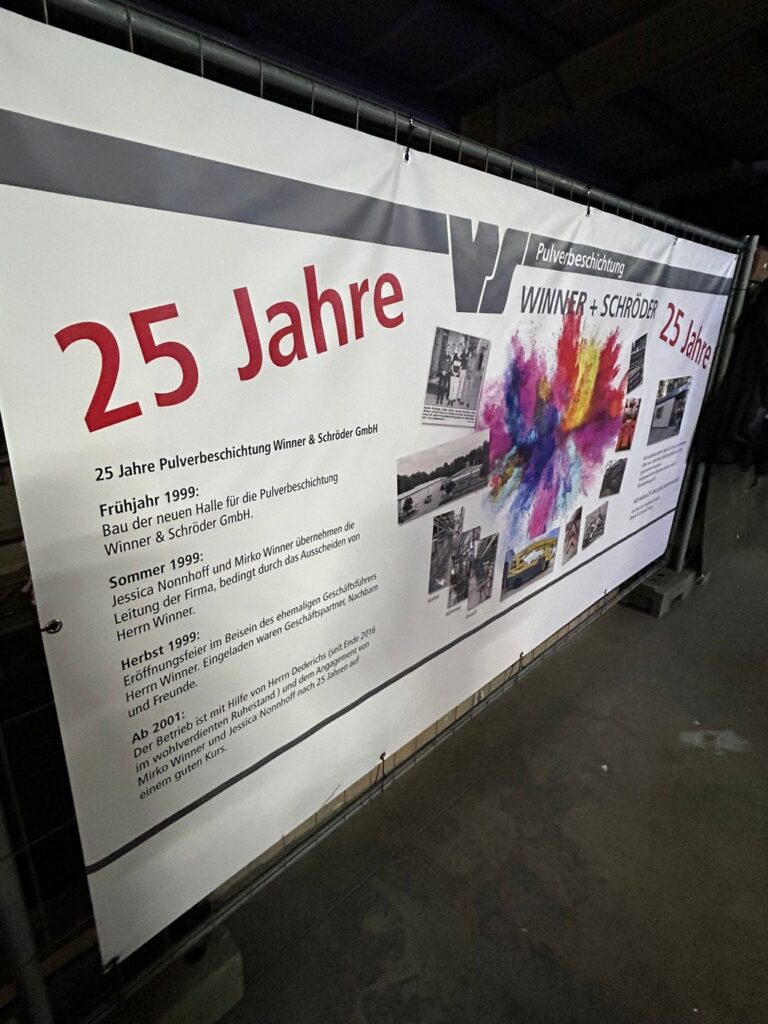 Ein großes Banner mit buntem Farbspritzer und Fotos feiert 25 Jahre Jubiläum