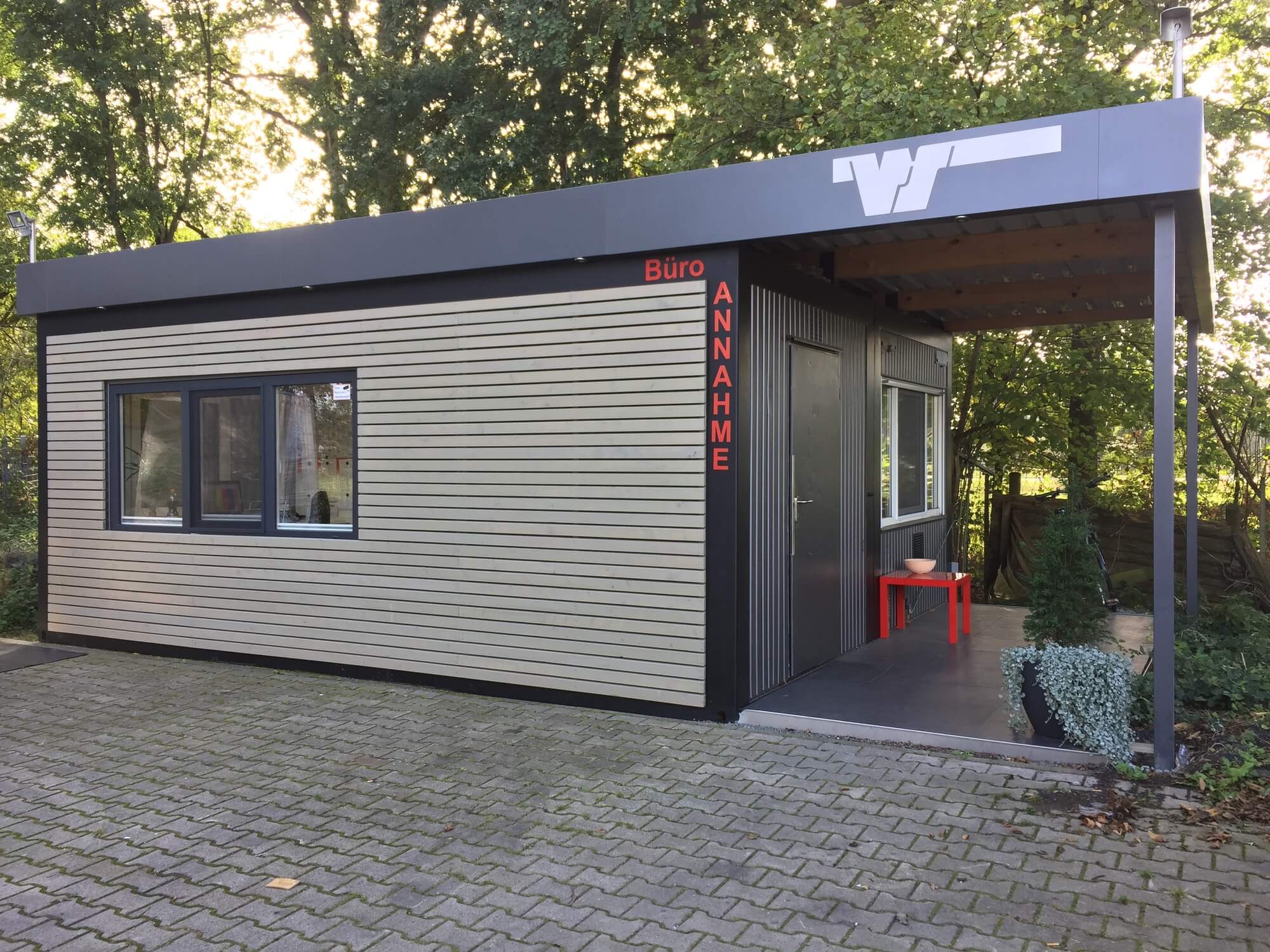 Ein modernes Bürogebäude mit Holzverkleidung und großem Fenster steht im Grünen